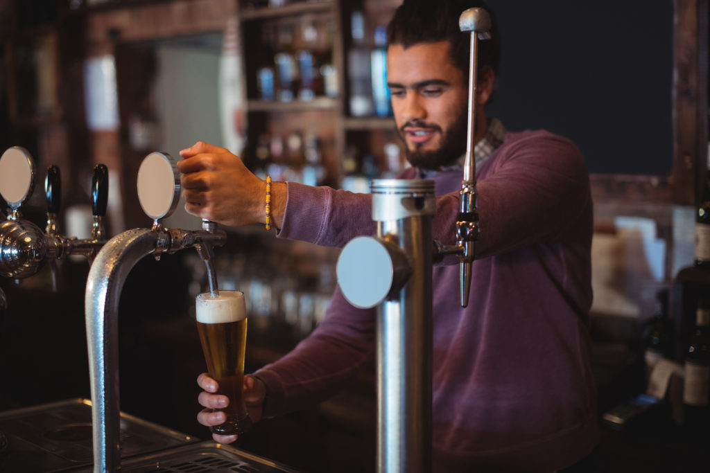 Bartender filling beer from bar pump at bar counter