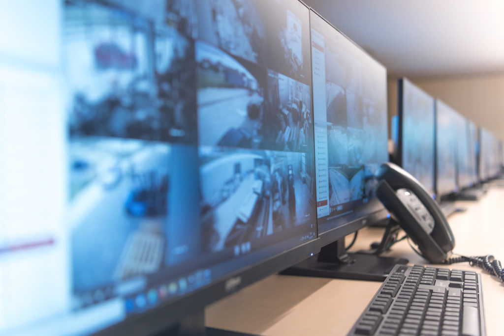 Security guard monitoring modern CCTV cameras in surveillance room.