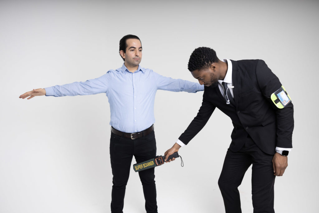 Security professional conducting a metal detector scan on an individual, highlighting event security and SIA licence requirements.