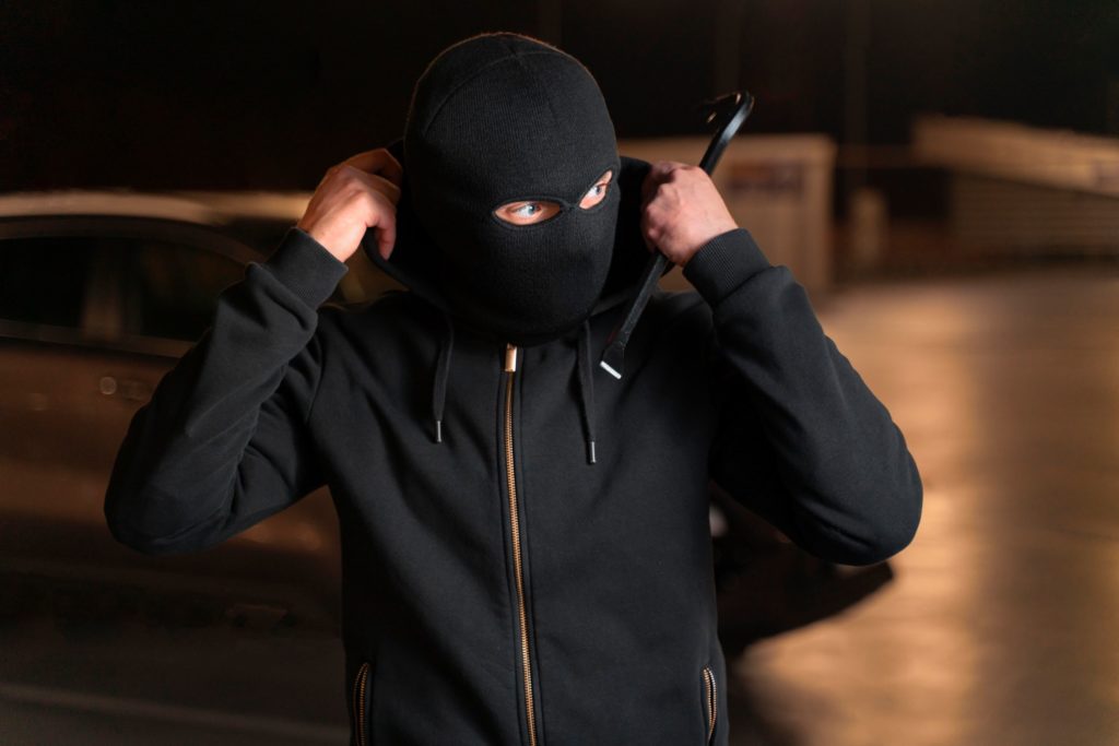 Man in ski mask and hoodie holding a crowbar, symbolising the threat of theft faced by UK businesses and the need for SIA security.