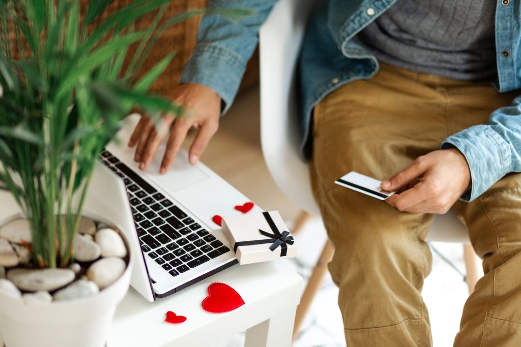 Man using laptop computer and credit card, ordering gifts for Valentines day, Womans Day, Christmas. Shopping online during holidays